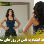 زن ایستاده در حالت قدرت جلوی آینه، دست‌ها روی کمر